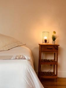 Una cama con mesita de noche con una lámpara. en Hospedaje de la Costa en Tigre