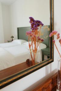un espejo con un jarrón de flores sobre una mesa en Hotel Rural Salvatierra, en Salvatierra de Tormes