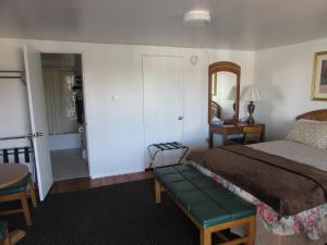 1 dormitorio con cama, mesa y espejo en Mel Haven Motel, en Colorado Springs