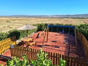a playground with a swing and a table and an umbrella at Prasonisi Villas in Kattavía