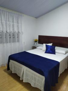 a bedroom with a large bed with a blue blanket at Hospedagens Som das Aguas in Alto Caparao