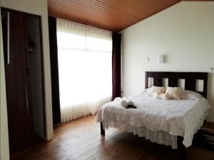 a bedroom with a bed with white sheets and a window at Hotel Vistas del Cielo in Cartago