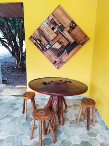 een houten tafel en krukken voor een gele muur bij Hospedagens Som das Aguas in Caparaó Velho
