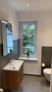 ein Bad mit einem Waschbecken, einem WC und einem Fenster in der Unterkunft Landgasthof Alter Krug Potsdam OT Marquardt in Potsdam