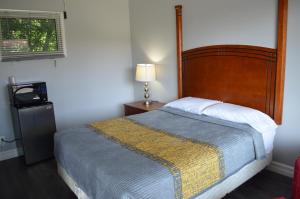 1 dormitorio con 1 cama grande y TV en Studio 1 Motel en Cobourg