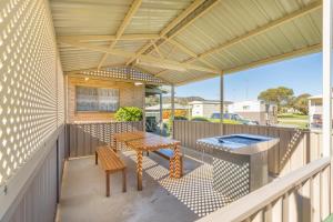 un patio con una mesa y bancos en una terraza en Tasman Holiday Parks - Serpentine Falls, en Serpentine