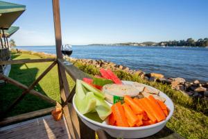 a bowl of vegetables on a table with a glass of wine at BIG4 Batemans Bay at Easts Riverside Holiday Park in Batemans Bay