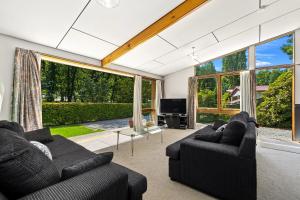 a living room with two black couches and a large window at Merioneth Retreat - Arrowtown Holiday Home in Arrowtown