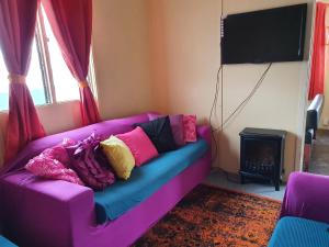 un sofá púrpura con almohadas en la sala de estar en Golden Mt Rest on James en Mount Morgan