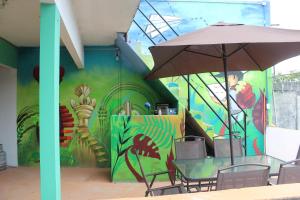 een tafel met een paraplu voor een muurschildering bij Sukha Hostel Xilitla in Xilitla