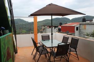 a table and chairs with an umbrella on a balcony at Sukha Hostel Xilitla in Xilitla