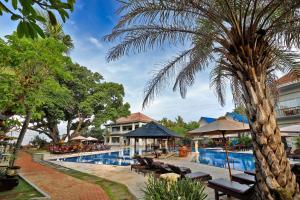 ein Resort mit einem Pool und einer Palme in der Unterkunft Puri Saron Hotel Seminyak in Seminyak