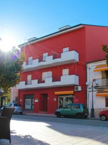 a red building with cars parked in front of it at La Postale in San Salvo