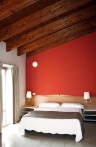 a bedroom with a red wall and a bed at Hotel La Rosta in Reggio Emilia