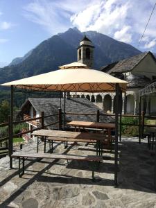 una mesa de picnic con una sombrilla frente a un edificio en Rifugio Monte Zeus, en Baceno