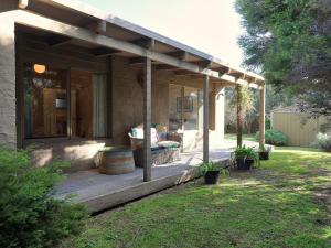 a house with a wooden porch with a bench on it at Back Beach Hideaway in Blairgowrie