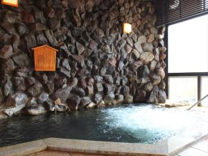 una pared de roca con una piscina de agua delante en Ryokan Biyunoyado, en Yamanouchi