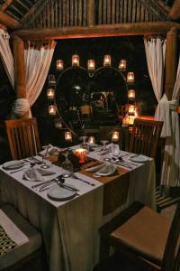 a dining room table with chairs and lamps at Munduk Moding Plantation Nature Resort & Spa in Munduk