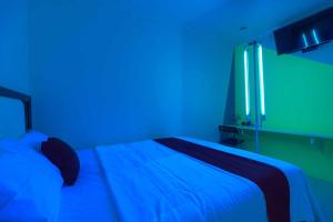 a bedroom with a bed with blue and green lights at RedDoorz @ Taman Galaxy Bekasi in Cikunir Satu