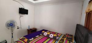 a bedroom with a bed with a pillow and a fan at Limasan Mbah Darmo in Tepus