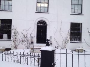 林頓的住宿－St Vincent Guest House，坐在房子前面的围栏上的猫
