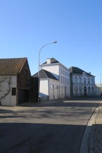 una strada vuota con edifici bianchi e un lampione di B&B / Studio De Druivelaar in hartje Kluisbergen (Berchem) a Kluisbergen