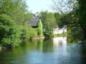 une rivière avec une maison sur son côté dans l'établissement Auberge de Jeunesse HI Pontivy, à Pontivy