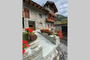 een stenen huis met rode bloemen op de trappen bij La Cachette CIR 0001 in Aosta