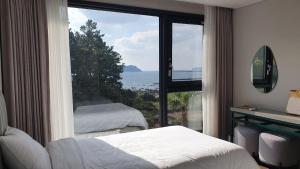 a bedroom with a large window with a view of the ocean at Hotel Seogwipean in Seogwipo