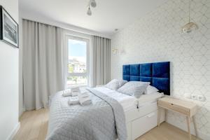 a bedroom with a large bed with a blue headboard at Dom & House - Apartments Navio Estate in Gdańsk