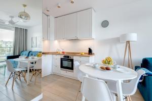 a kitchen and living room with white cabinets and a table and chairs at Dom & House - Apartments Navio Estate in Gdańsk