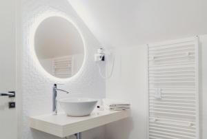W białej łazience znajduje się umywalka i lustro. w obiekcie Casa Del Sole w mieście Alba Iulia