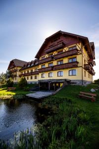 a large building with a pond in front of it at Apartmány DeLuxe Lomnica in Veľká Lomnica