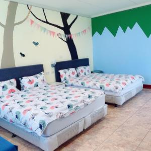 two beds in a room with trees on the wall at Backstreet Inn in Xiluo