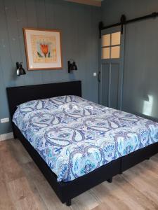 B & B Tulp Amsterdam Noord في أمستردام: سرير لحاف من اللون الأزرق والأبيض في غرفة النوم