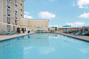 una gran piscina con sillas y sombrillas en Holiday Inn - Beaumont East-Medical Ctr Area, an IHG Hotel, en Beaumont
