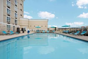 a large swimming pool with chairs and umbrellas at Holiday Inn - Beaumont East-Medical Ctr Area by IHG in Beaumont