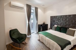 a bedroom with a bed and a green chair at Locanda Il Carugio in Corniglia