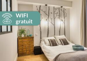 a bedroom with a bed with a tree mural on the wall at Cosy Appartement Lyon Valmy - parking in Lyon