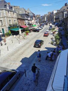a man walking a bike down a street with cars at Studio des Stuarts in Dol-de-Bretagne +4 photos