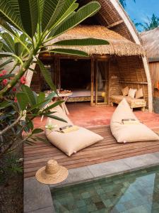 een hut met kussens op een houten terras naast een zwembad bij Villa Palma Gili Meno - Private Pool in Gili Meno