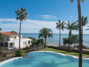 una piscina con palme e l'oceano di Apartamentos Casablanca Marineu ad Alcossebre