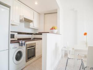 cocina blanca con lavadora y mesa en Apartamentos Casablanca Marineu, en Alcossebre