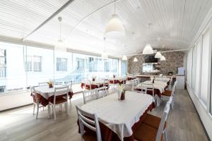 a restaurant with white tables and chairs and windows at Noviz Hotel in Plovdiv