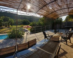 een patio met een tafel en stoelen en een zwembad bij Moulin de Bonfilhon in Cornillon-Confoux
