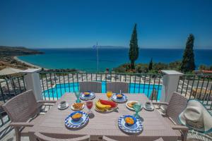 een houten tafel met eten op het balkon bij Garbis Villas & Apartments in Lourdhata