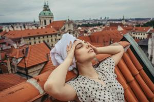 a woman sitting on top of a building in the middle of the day at Residence Thunovska in Prague