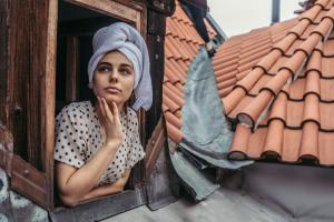 a woman sitting in front of a window with a bird on her head at Residence Thunovska in Prague