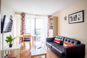 sala de estar con sofá de cuero negro y mesa en City One Bed in West One Apartments en Sheffield