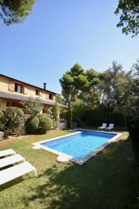 una piscina in un cortile con sedie e una casa di Casa Feliz a Sant Cebrià de Vallalta